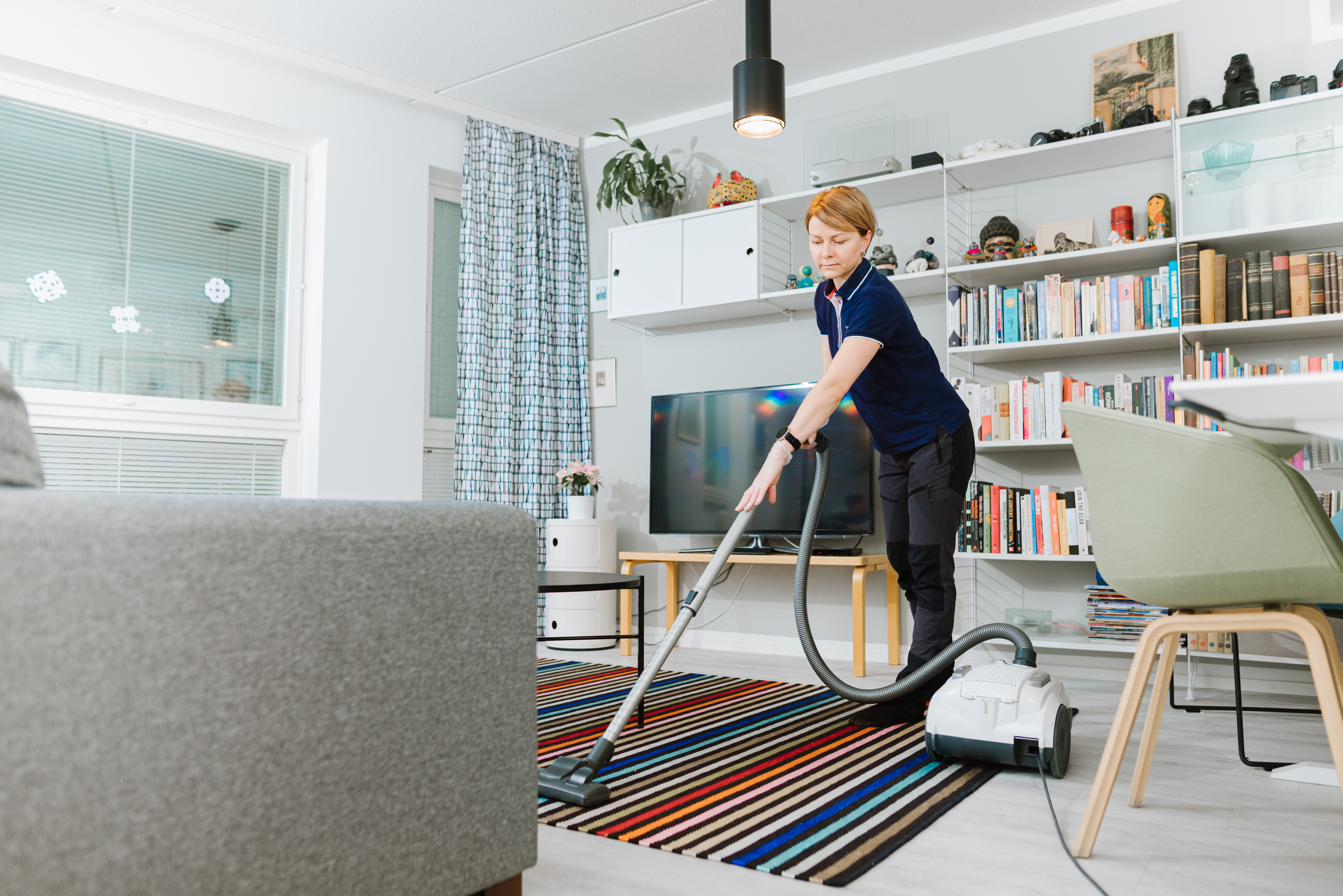 Kotisiivooja imuroi olohuoneessa